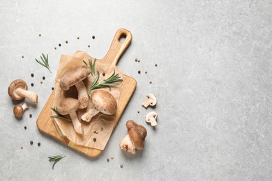 Flat lay composition with fresh wild mushrooms on light grey table, space for text