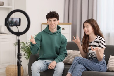 Smiling teenage bloggers talking while streaming at home