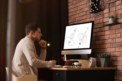 Image of Male engineer working with technical drawing on computer in office