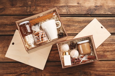 Boxes with stylish craft gift sets on wooden table, flat lay