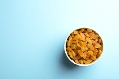 Photo of Bowl of raisins on color background, top view with space for text. Dried fruit as healthy snack