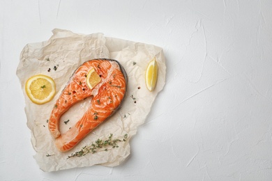 Fresh raw salmon steak with seasonings on light background, top view