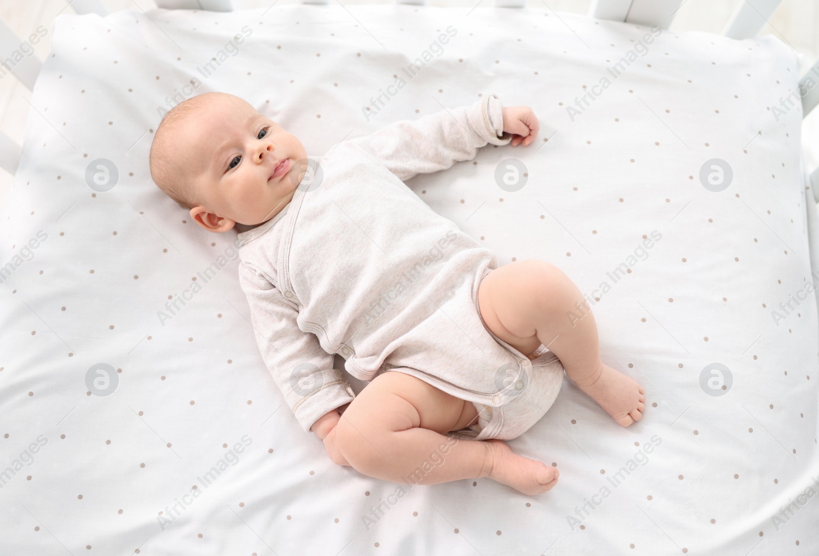 Photo of Cute little baby lying in crib at home, top view