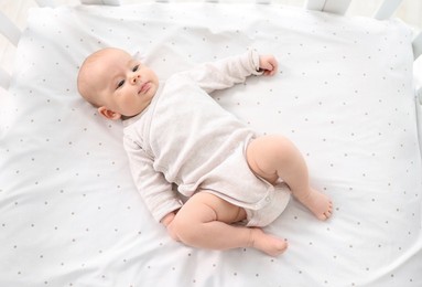 Cute little baby lying in crib at home, top view