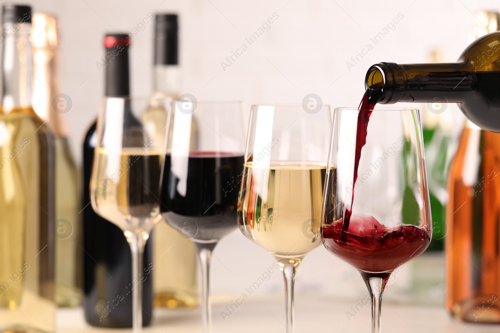 Photo of Pouring red wine from bottle into glass, closeup