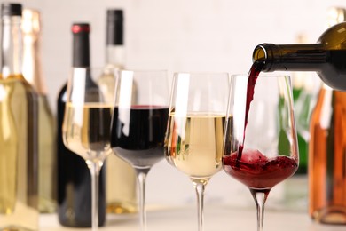 Photo of Pouring red wine from bottle into glass, closeup