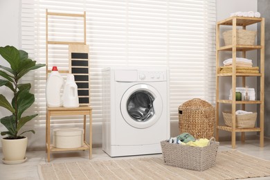 Photo of Laundry room interior with washing machine, baskets and houseplant