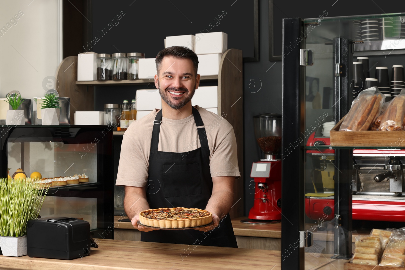 Photo of Business owner in his cafe. Man presenting delicious quiche at desk