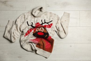 Warm Christmas sweater on wooden table, top view