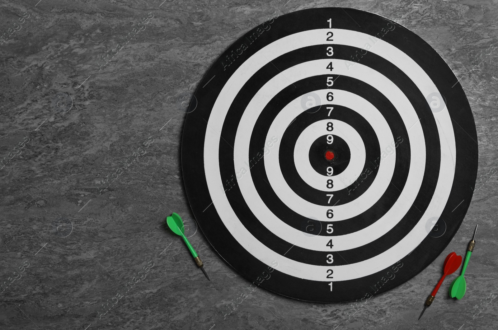 Photo of Dart board with color arrows on grey stone background, top view. Space for text