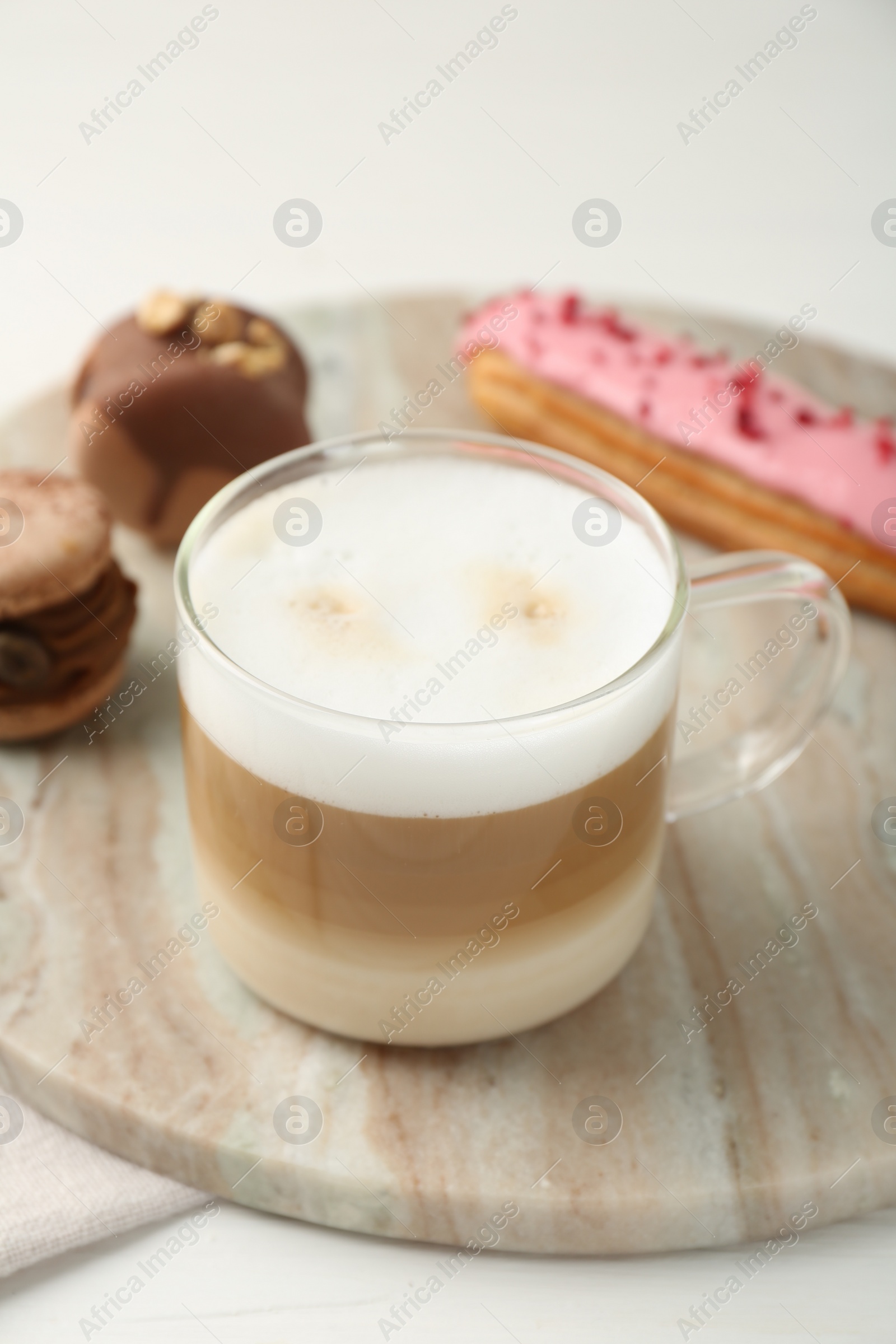 Photo of Aromatic coffee in cup, tasty macarons and eclair on white table