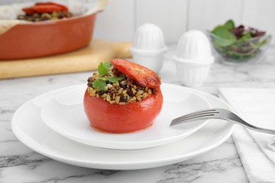 Delicious stuffed tomato with minced beef, bulgur and mushrooms on white marble table