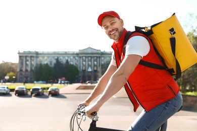 Photo of Male courier on bicycle delivering food in city