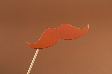 Photo of Fake paper mustache party prop on light brown background