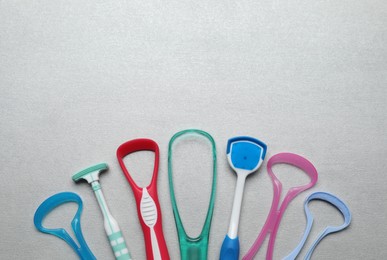 Photo of Different tongue cleaners on light grey table, flat lay. Space for text