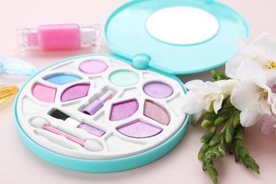 Photo of Decorative cosmetics for kids. Eye shadow palette, accessories and flowers on pink background, closeup