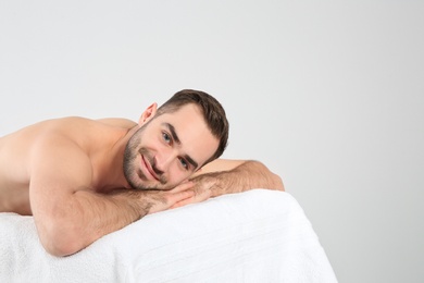 Photo of Handsome man relaxing on massage table against white background. Spa service