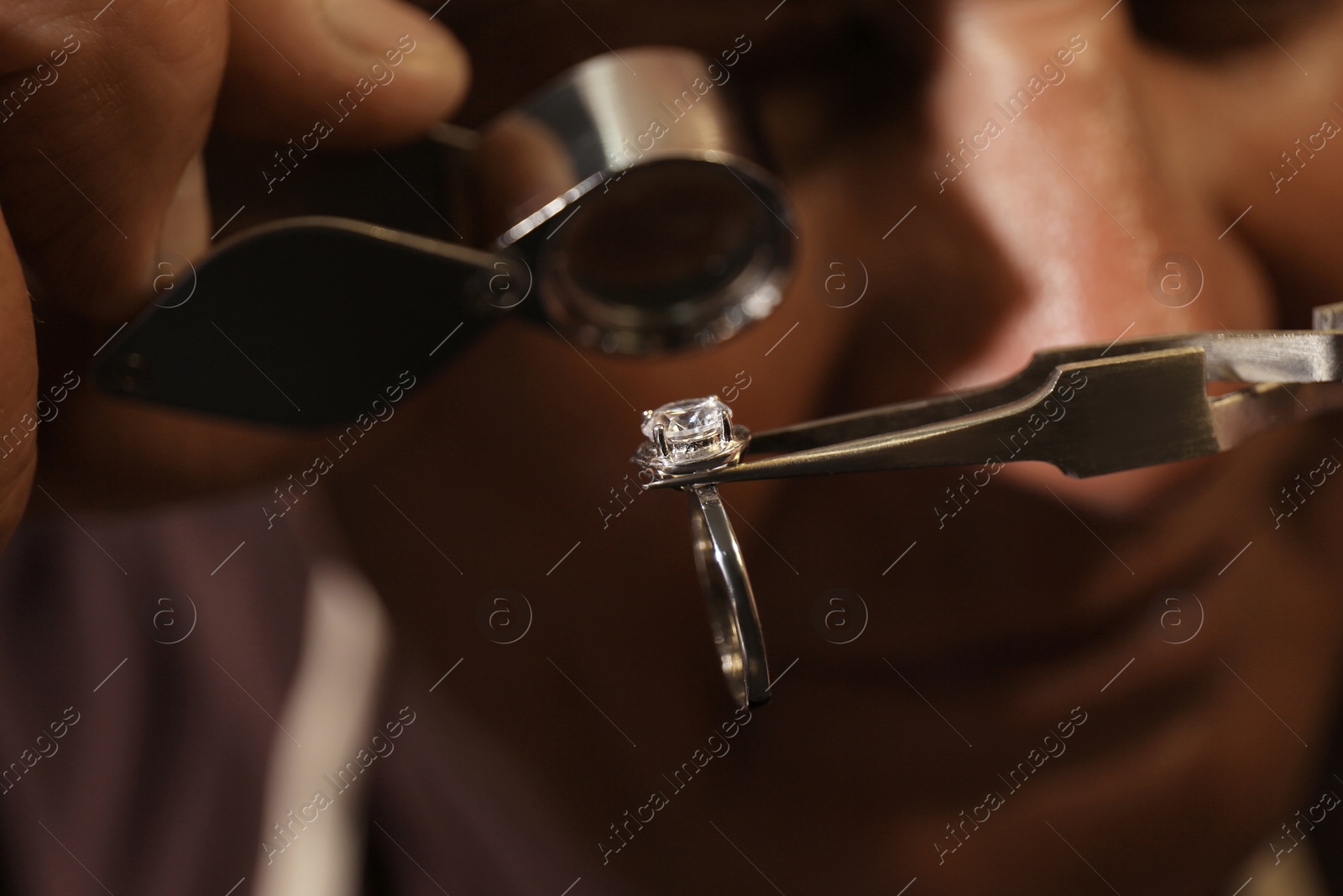 Photo of Professional jeweler evaluating beautiful ring, closeup view