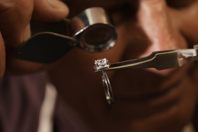 Professional jeweler evaluating beautiful ring, closeup view