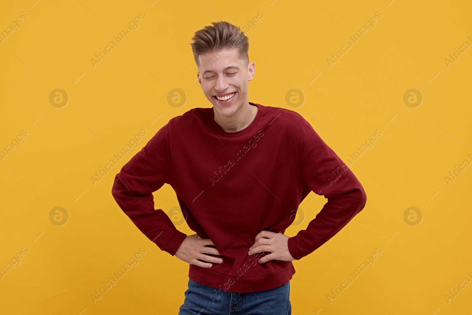 Photo of Portrait of young man laughing on orange background