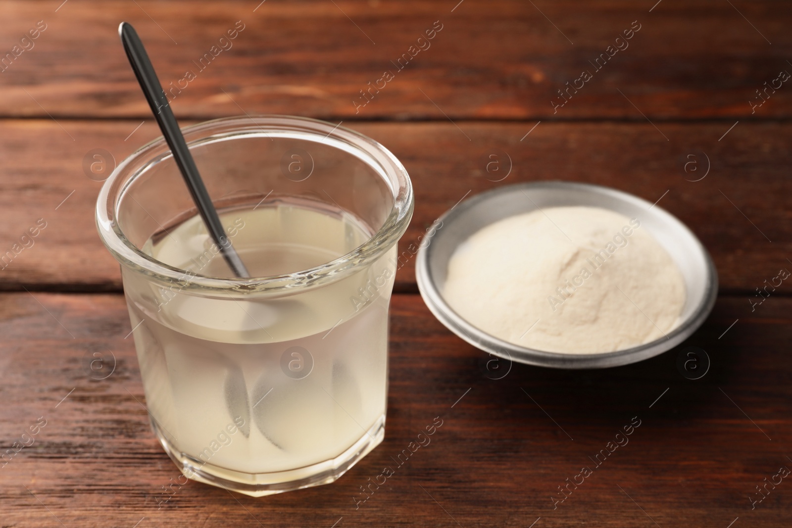 Photo of Glass of agar-agar jelly and bowl with powder on wooden table