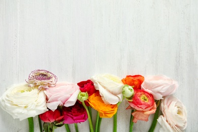 Photo of Beautiful ranunculus flowers and space for text on wooden background, flat lay