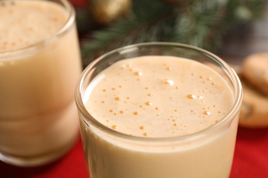 Photo of Tasty eggnog, cookies and fir branches on table, closeup