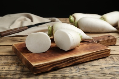 Photo of Cut and whole white turnips on wooden table