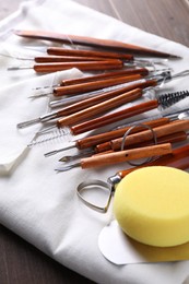 Photo of Set of different clay crafting tools on wooden table, closeup