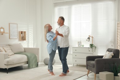 Photo of Happy senior couple dancing together in living room