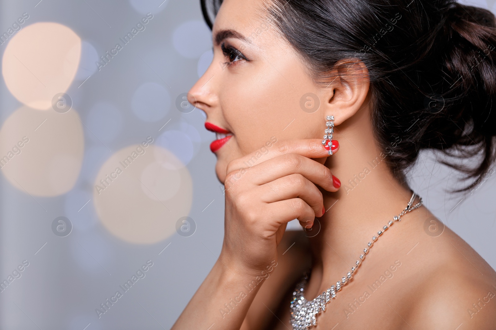 Photo of Beautiful woman with elegant jewelry on blurred background, closeup. Space for text