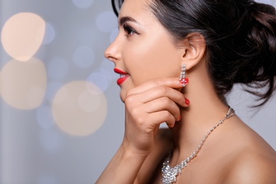 Photo of Beautiful woman with elegant jewelry on blurred background, closeup. Space for text