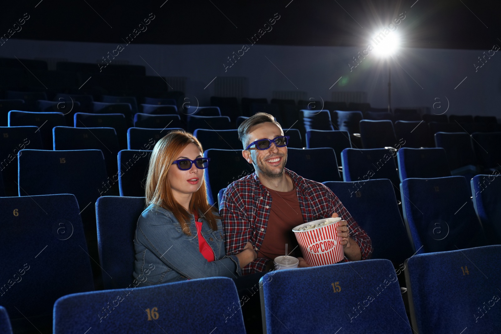 Photo of Young couple with popcorn watching movie in cinema theatre