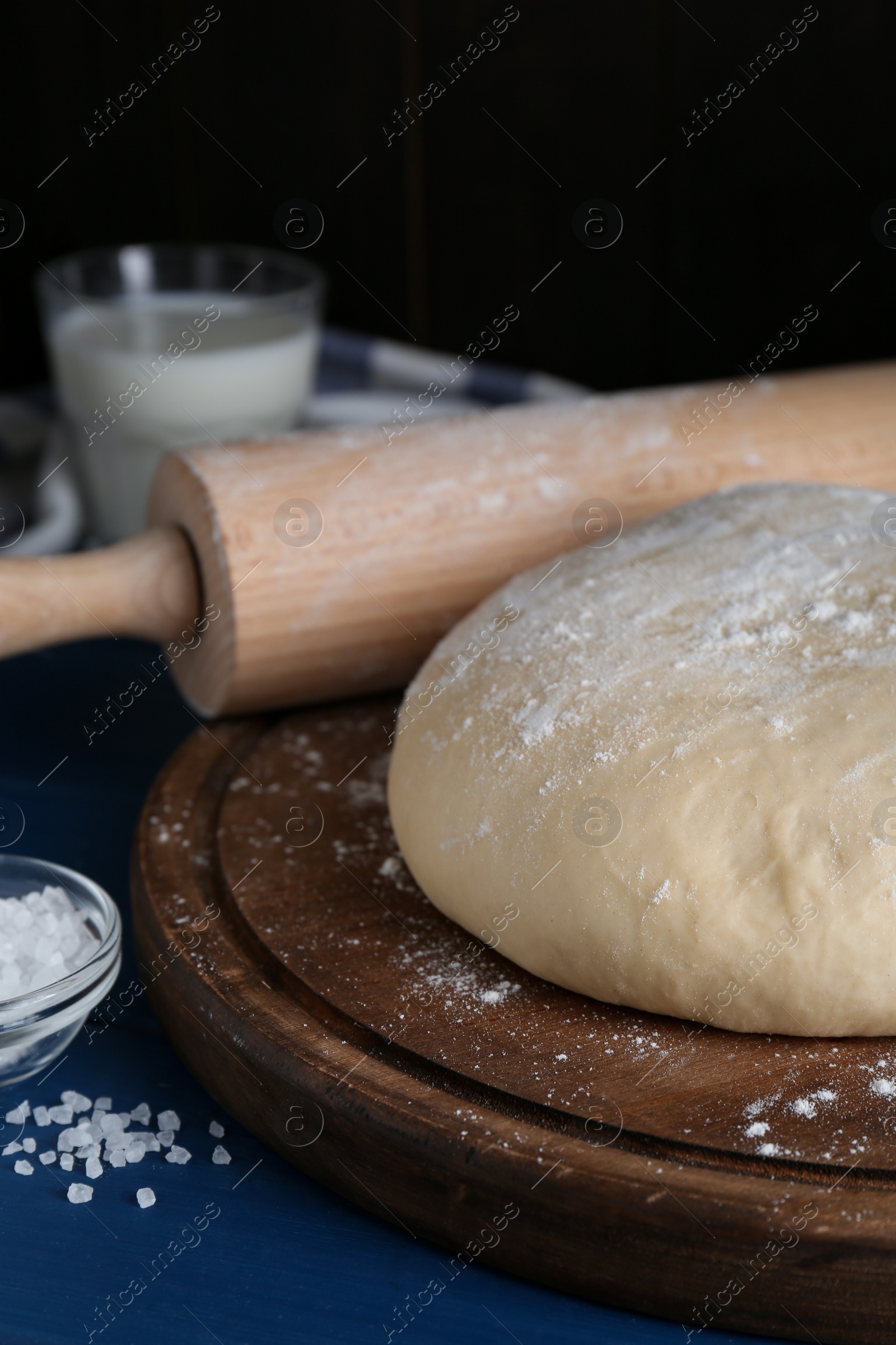 Photo of Fresh yeast dough with flour on blue wooden table, closeup