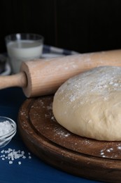 Fresh yeast dough with flour on blue wooden table, closeup