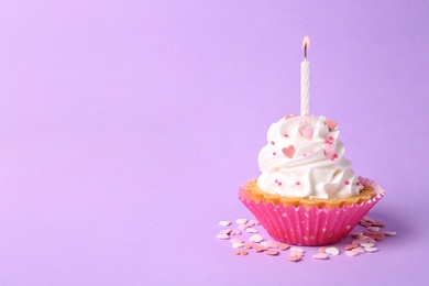 Photo of Delicious cupcake with candle on violet background. Space for text