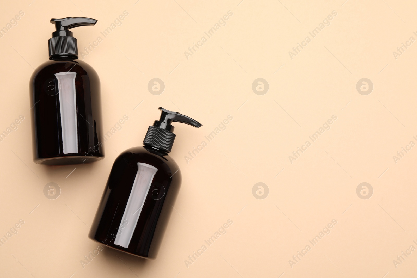 Photo of Bottles of shampoo on beige background, flat lay. Space for text