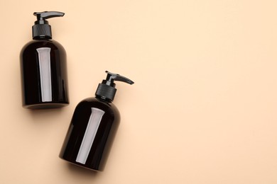 Bottles of shampoo on beige background, flat lay. Space for text