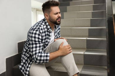 Photo of Man fallen down stairs suffering from pain in knee indoors