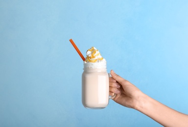 Photo of Woman holding mason jar with delicious milk shake on color background