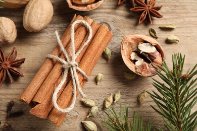 Photo of Different spices, nuts and fir branches on wooden table, flat lay