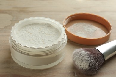 Photo of Rice loose face powder and makeup brush on brown table, closeup