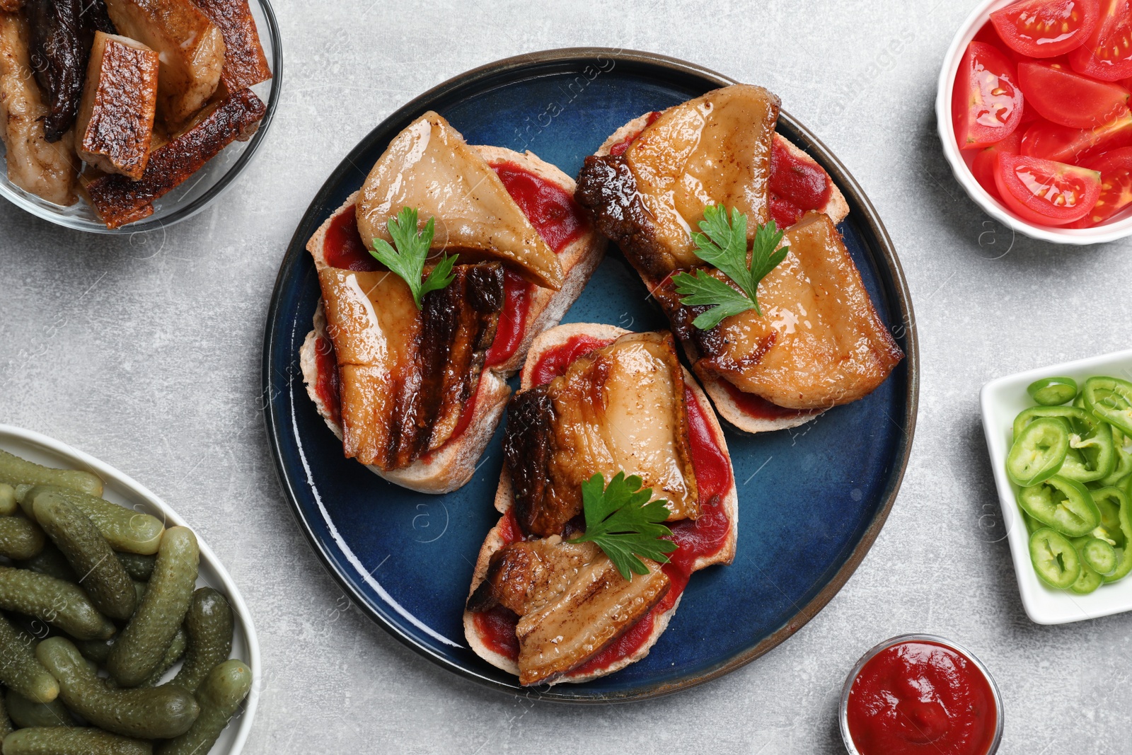 Photo of Tasty sandwiches with fried pork fatback slices on light grey table, flat lay