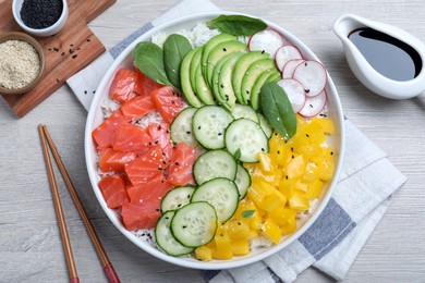 Delicious poke bowl with salmon and vegetables served on wooden table, flat lay