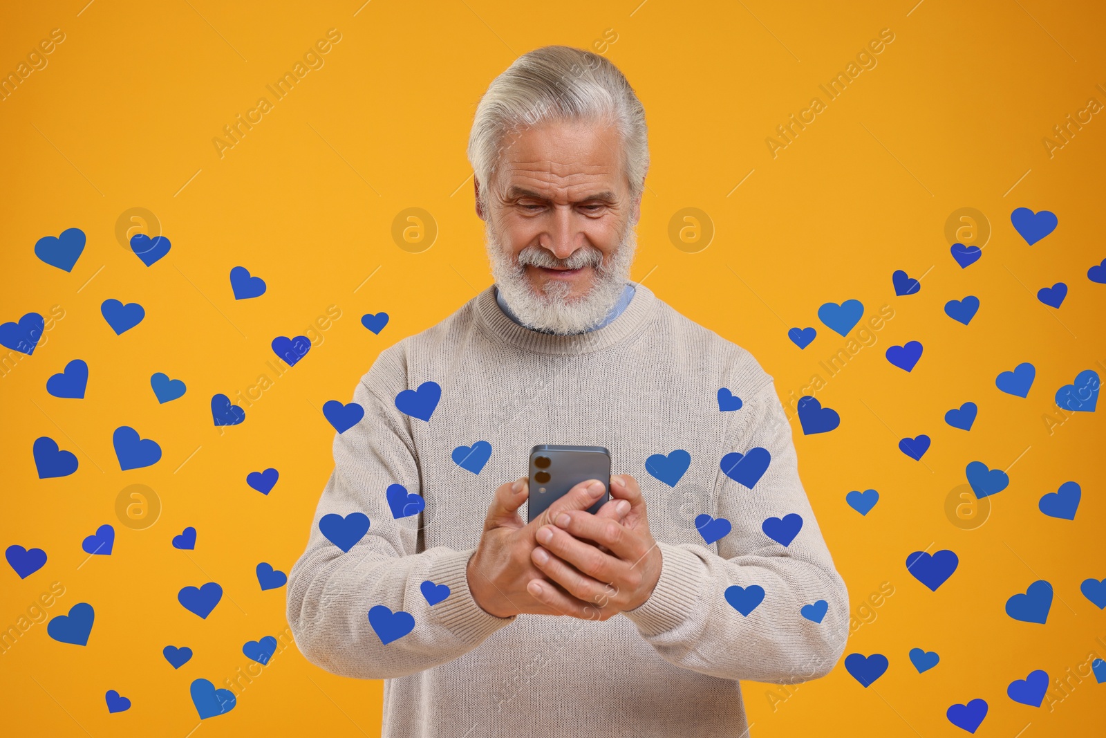 Image of Long distance love. Man chatting with sweetheart via smartphone on golden background. Hearts flying out of device and swirling around him