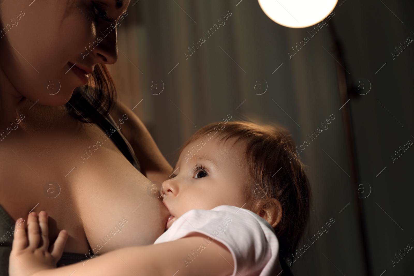 Photo of Woman breastfeeding her little baby at home, closeup