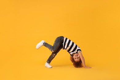 Happy little boy dancing on yellow background. Space for text