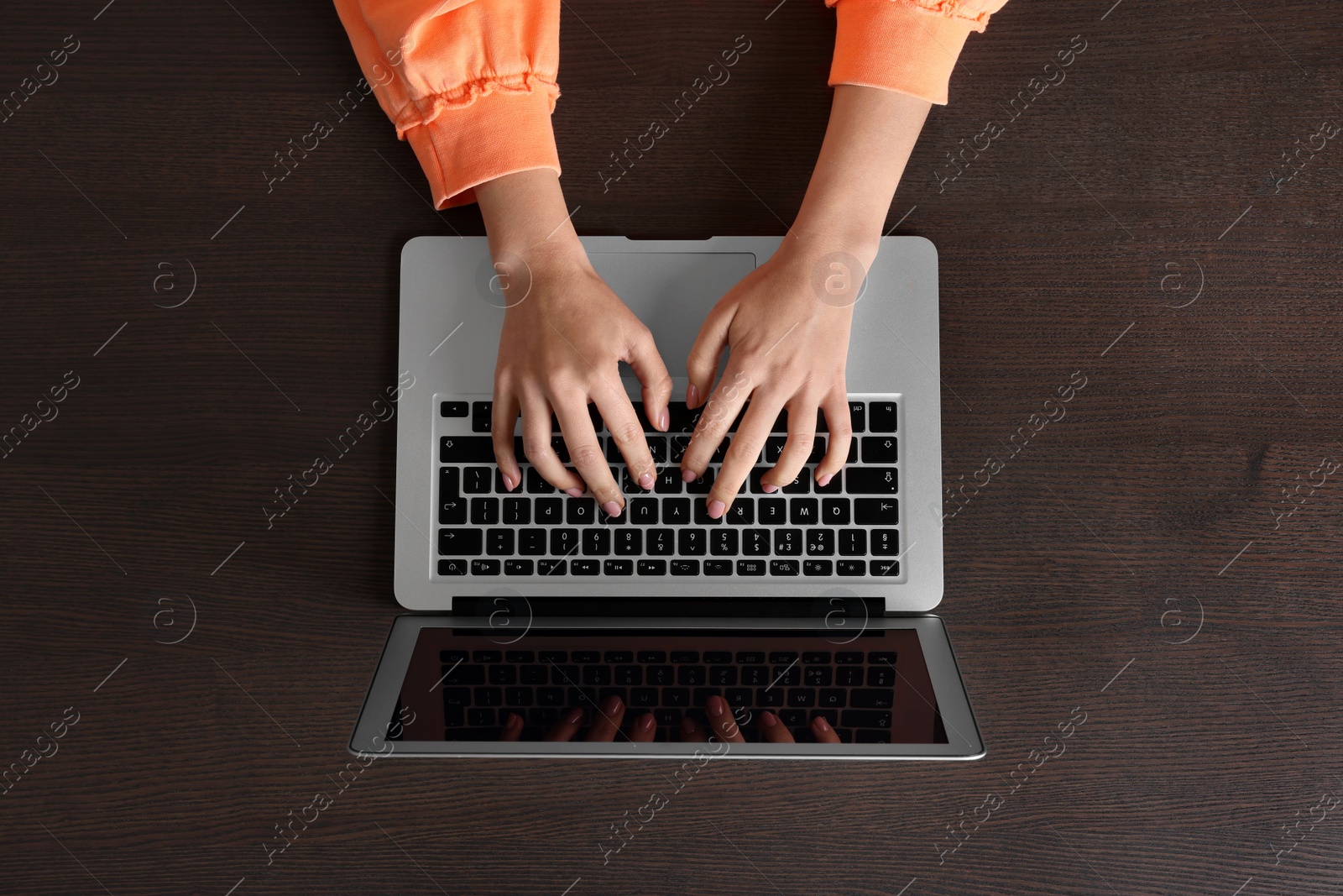 Photo of Woman working with laptop at wooden table, top view