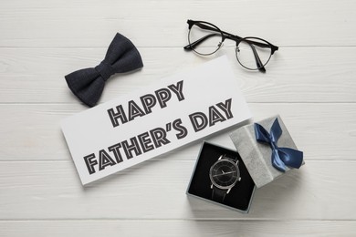 Photo of Card with phrase HAPPY FATHER'S DAY, eyeglasses, bow tie and wristwatch on white wooden background, flat lay