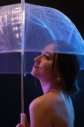 Photo of Beautiful woman with umbrella on dark background in neon lights